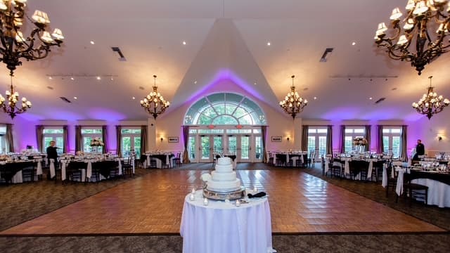 Elegant wedding reception ballroom with purple uplighting and chandeliers